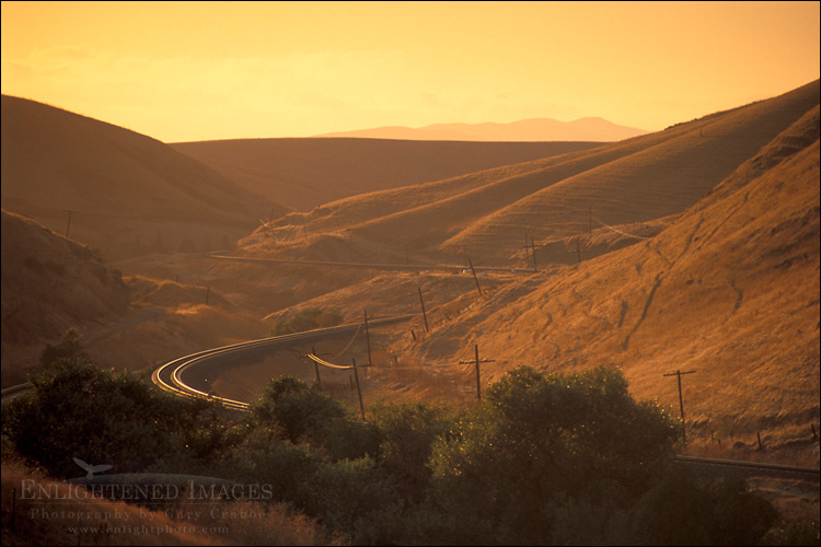 Photo: Golden sunset light on curve railroad tracks through grass hills in summer, Altamont Pass, Alameda County, California