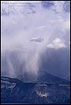 Picture: Mount Scott, lake, water storm, stormy, storm clouds, cloud, clouds, cloudy, rain, raining, rainstorm, rain storm, sunlight, sunlit, weather, percipitation climate, grey, gray, crater, wall, rim, steep, rugged, walls, volcanic, volcano,