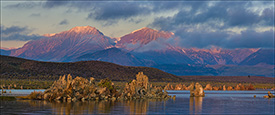 Picture: Alpenglow on mountains at sunrise seen through breaking clouds over Mono Lake, Eastern Sierra, California