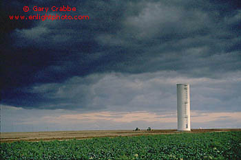 Spring storm clouds over tractors and silo in agricultural crop fields, Central Valley, California