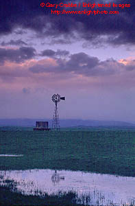 Windmill in pasture lands at sunset beneath spring storm clouds, Central Valley, California