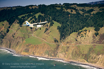 Small single-engine plane flying over the California coastal cliffs, Sonoma County, California