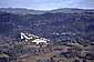 Small single engine fixed wing airplane (Maule) over wooded hills of Sonoma County, California