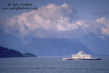 BC Ferry crossing the Queen Charlotte Channel beneath cloud covered coastal mountains, near Vancouver, British Columbia, Canada