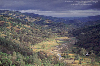 Sunlight through storm clouds on the rugged hills and stream in valley near Mount Hamilton, rural Santa Clara County, California