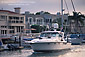 Luxury yacht Boat cruising through harbor channel next to waterfront homes at Newport Beach, California