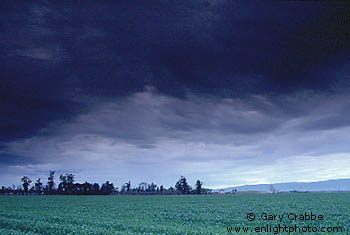 Dark grey rainstorm clouds over farmlands, California