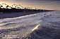 First rays of morning sunlight lights the top of a wave as it rolls onto the beach at Oceanside, San Diego County, California