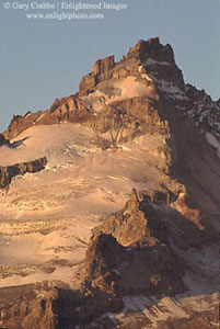 Golden light of sunrise on glacier-covered lava buttress high on Mount Rainier volcano, Mount Rainier National Park, Washington