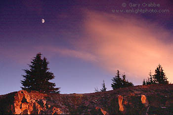 Moon rising over trees with red cloud in sky at sunset, from the rim of Crater Lake, Crater Lake National Park, Oregon