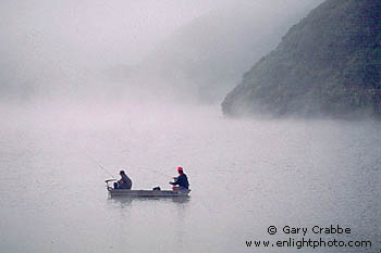 Two fishermen lake fishing from small boat on a misty morning, San Mateo Coast, California
