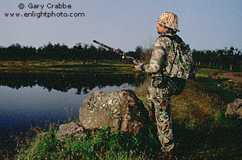 Hunter in camouflage looking for signs of waterfowl, Tehema County, California