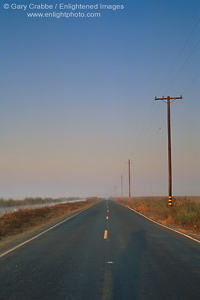 Picture: Straight two lane levee road through flat open area, San Joaquin River Delta, California