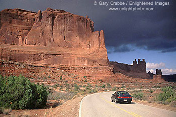 Driving below red cliffs near Park Avenue, Arches National Park, Utah