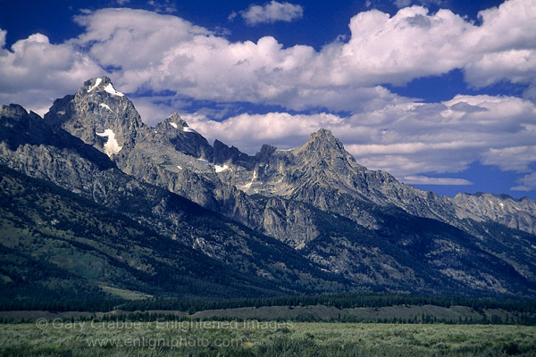 Photo: Blue sky and puffy white clouds over steep rising mountains at Grand Teton National Park, Wyoming