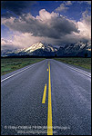Straight road below mountain range dusted by first snow of fall, Grand Teton National Park, WYOMING