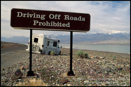 Driving off road prohibited Tourist RV tavel Camper stuck in desert rocks after drive offroad next to warning sign, near Badwater, Death Valley National Park, California