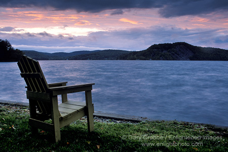 Wooden deck chair and storm clouds at sunset over Lake Bomoseen, near Rutland, Berkshire region, Vermont