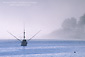 Commercial fishing boat in fog on calm blue water, San Simeon Bay, Central Coast, California