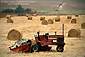 Farm tractor and hay bale rolls in field near Cambria, Central Coast, California