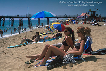 Young women in sunbathing on crowded sand beach at Balboa Pier, Newport Beach, Orange County, California