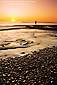 Person standing on pebble beach at sunset, Swami'a Beach, Encinitas, San Diego County Coast, California