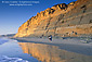 People walking on sand and golden cliffs reflected in water, Torrey Pines State Beach, near La Jolla, San Diego County Coast, California