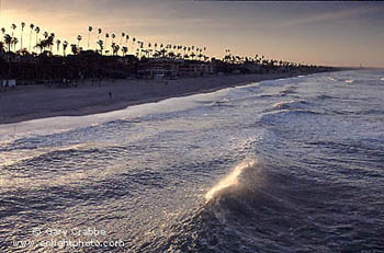 First rays of morning sunlight lights the top of a wave as it rolls onto the beach at Oceanside, San Diego County, California