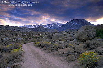 Stormy sunset over dirt road below the high mountain peaks of the Eastern Sierra, near Bishop, Inyo County, California