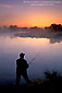 Lone fisherman fishing at sunrise in the San Joaquin River, Great Grasslands State Park, Central Valley, California