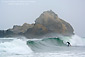 Surfer surfing the breaking waves next to coastal rock, Pfieffer Beach, Big Sur Coast, California