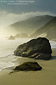 Coastal fog and rocks on sand beach along the rugged Big Sur Coast, California