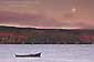 Full moon setting at sunrise over a lone dory in Tomales Bay, Marin County, California