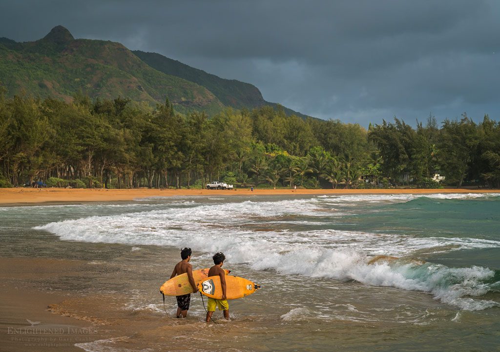 Photo: Pair of young male Surfers enter the surf water at Anahola Beach Park, Kauai, Hawaii