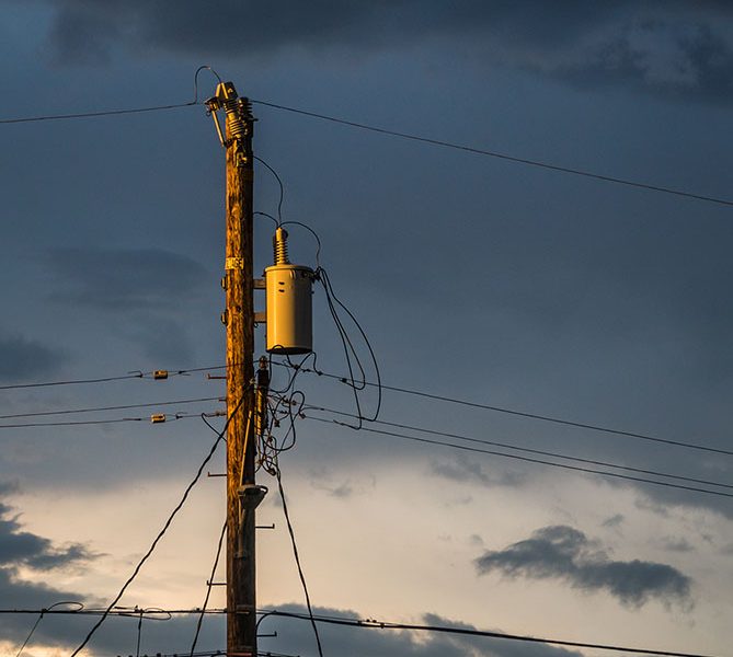 Photo: Stormy sunset light on electrical transformer box and telephone poles, Pleasant Hill, California