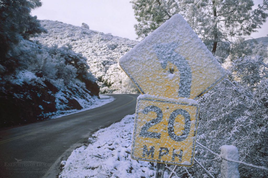 Photo picture of Slow speed Caution sign before curve in road covered in fresh snow, Alameda County, California