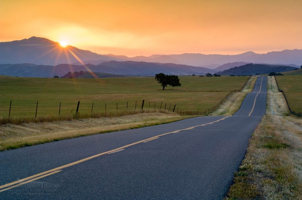 Photo picture of Golden sunrise light over long straight two lane country road and rolling hills in Spring, Santa Ynez Valley, California