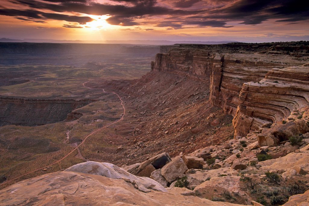 Photo Picture of Sunset and storm clouds over dirt road and layered sandstone rock cliffs above the San Juan River from Muley Point Overlook, Glen Canyon National Recreation Area, Utah